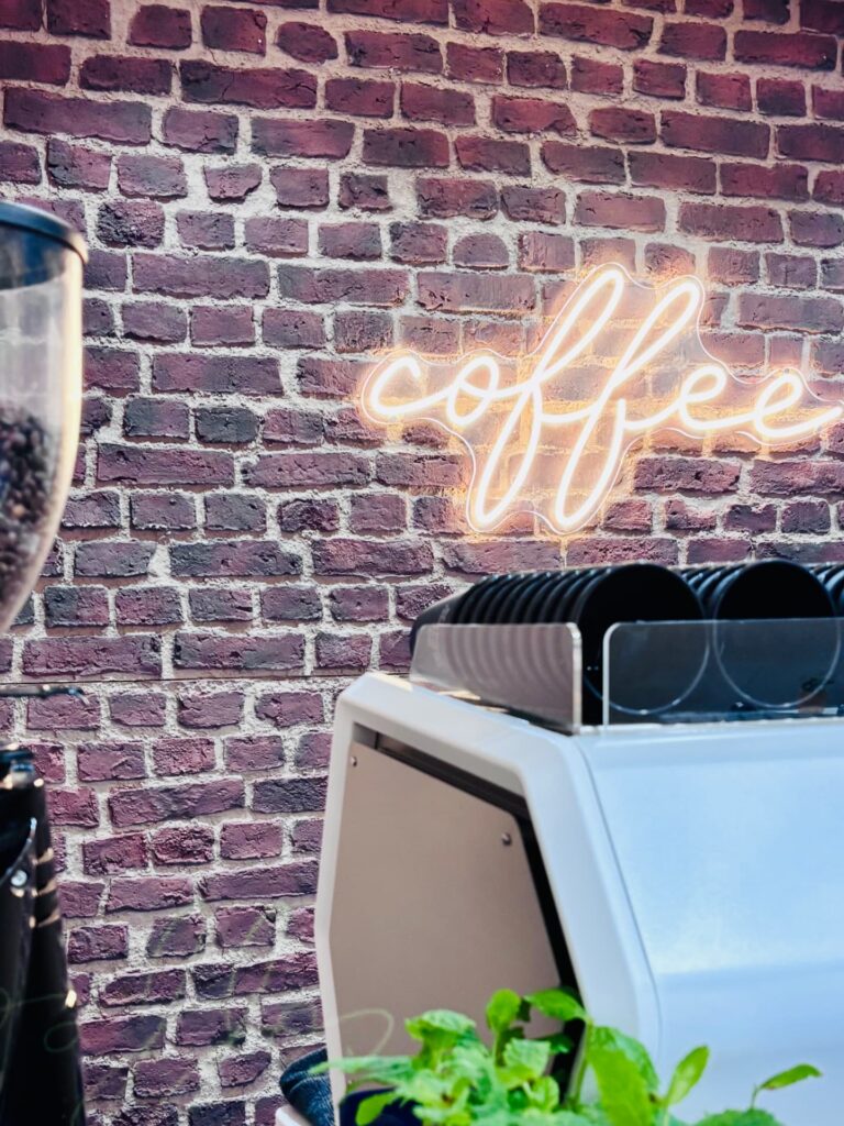Baristaservice van De Koffiejuf bij evenement in Amsterdam met neon coffee lichtbak en espressomachine